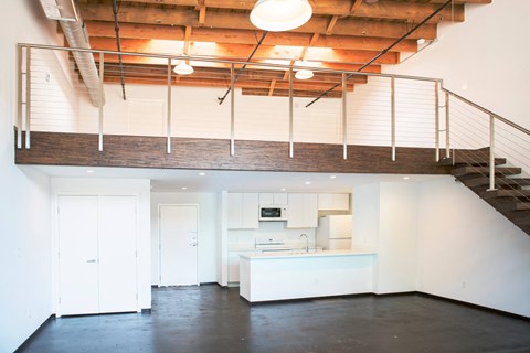 the kitchen is under a lofted ceiling with a staircase
